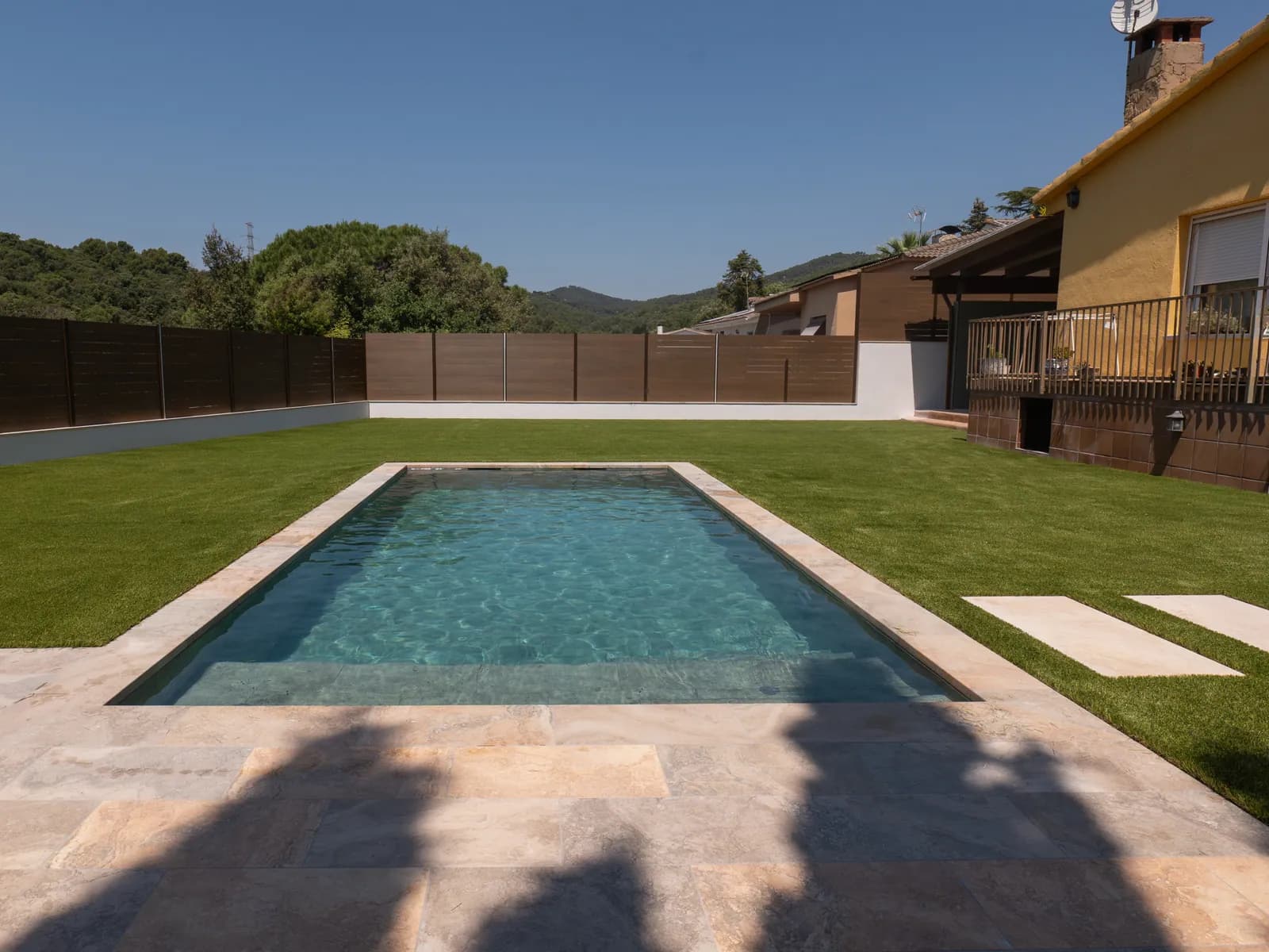 Piscina residencial con césped y zonas de paso