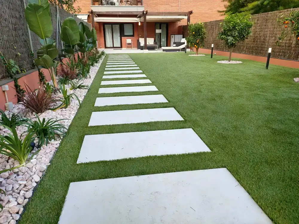 Jardín residencial con pasarela, pradera y composición vegetal