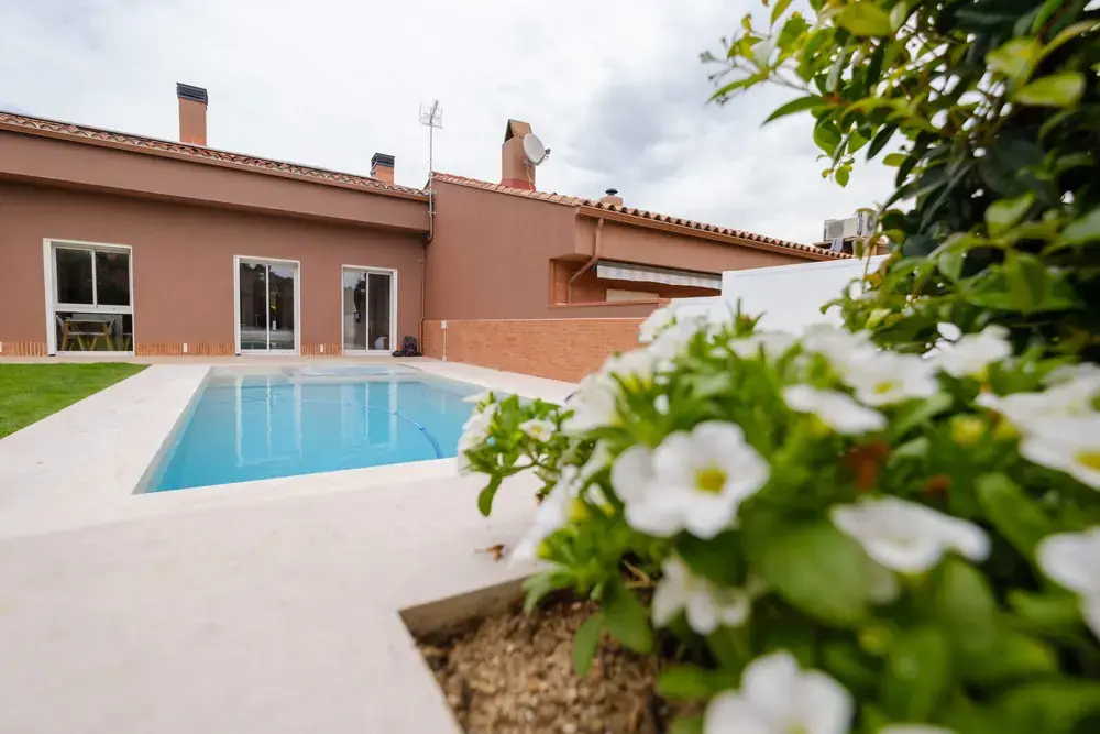 Piscina conectada con jardín y vivienda