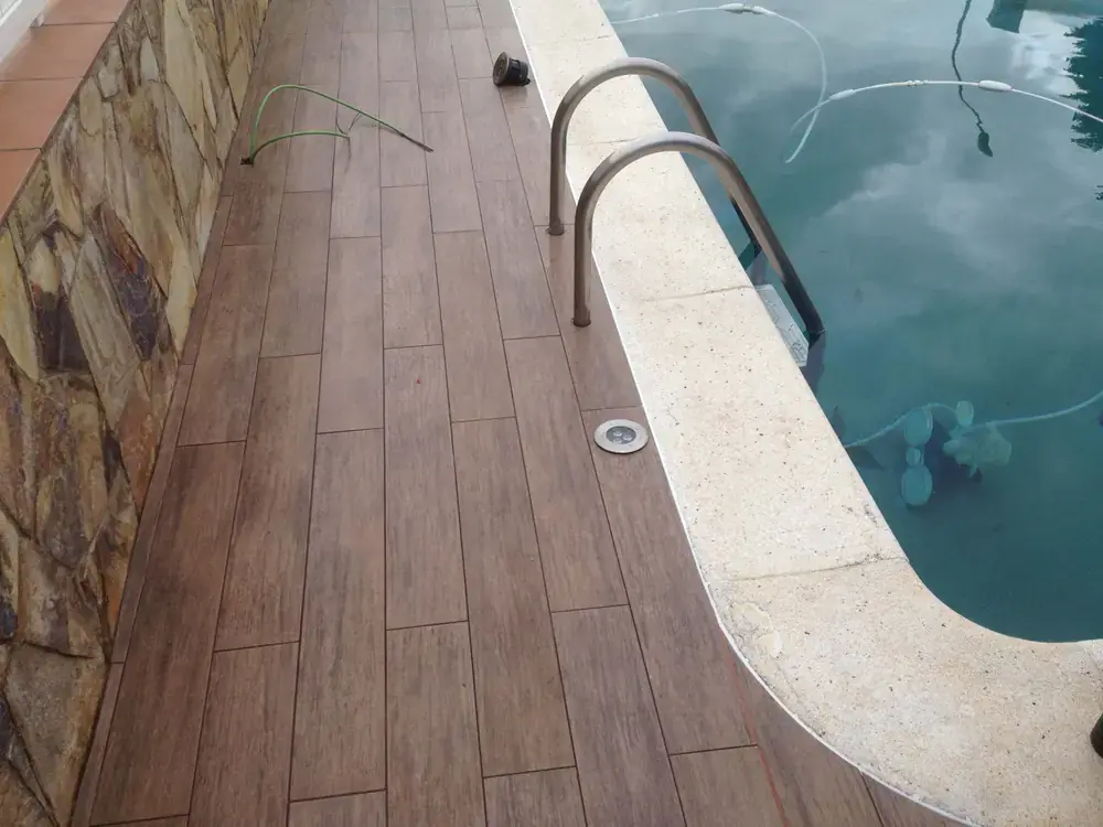 Pavimento porcelánico efecto madera junto a una piscina residencial