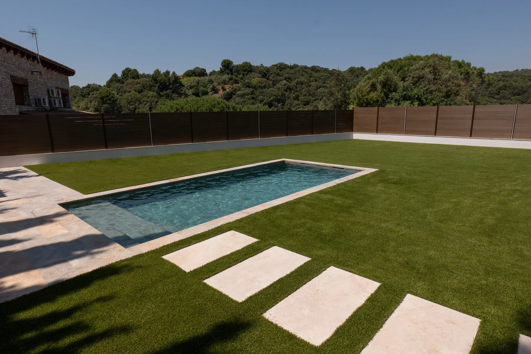 Piscina y jardín con césped artificial de aspecto natural