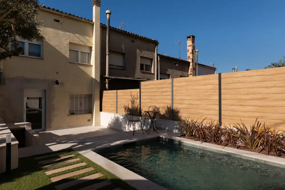 Piscina compacta con vallado y jardinería en un exterior urbano
