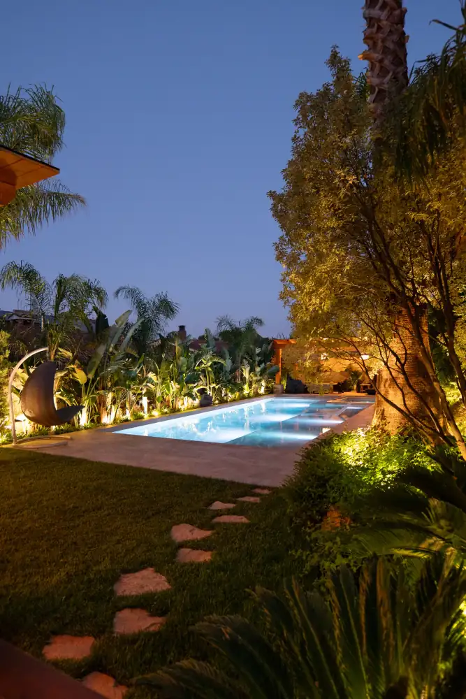 Piscina iluminada y paisajismo nocturno en un proyecto de exterior