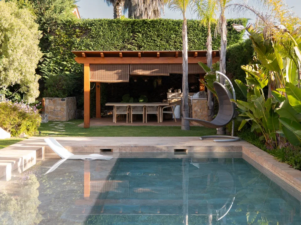 Pérgola de madera y vegetación junto a una piscina en Sant Quirze del Vallès