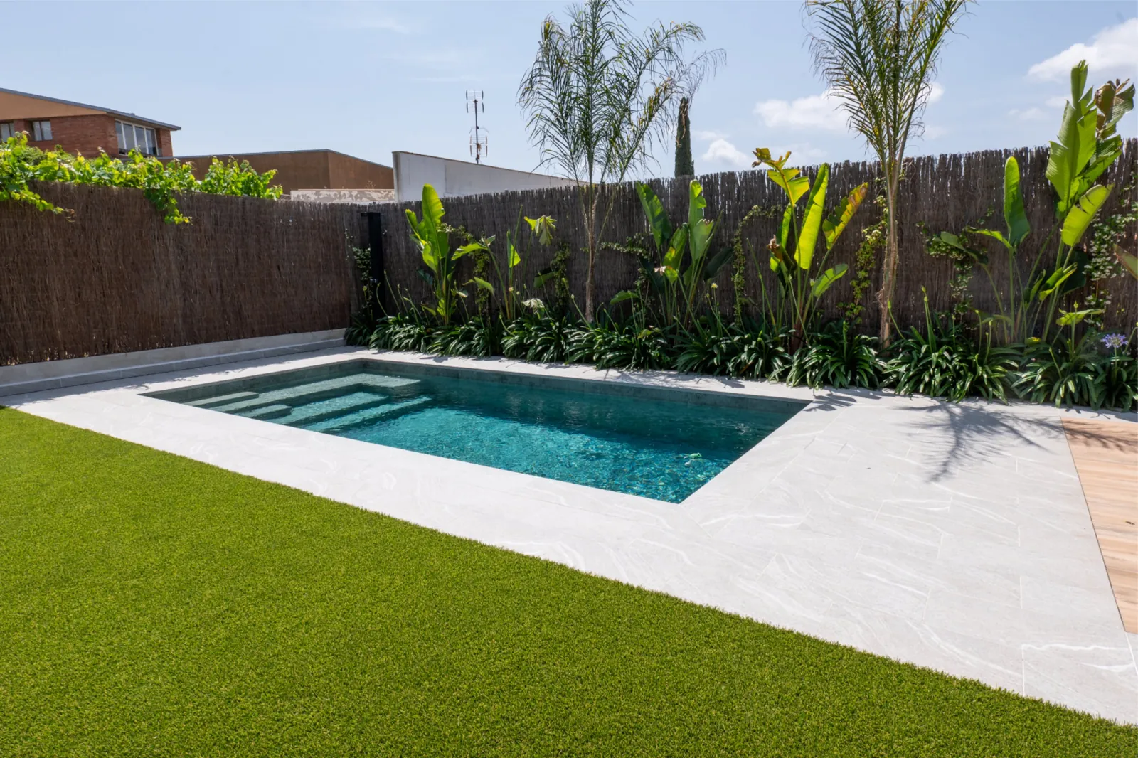 Piscina, césped artificial y camino de porcelánico en Calle Lleida