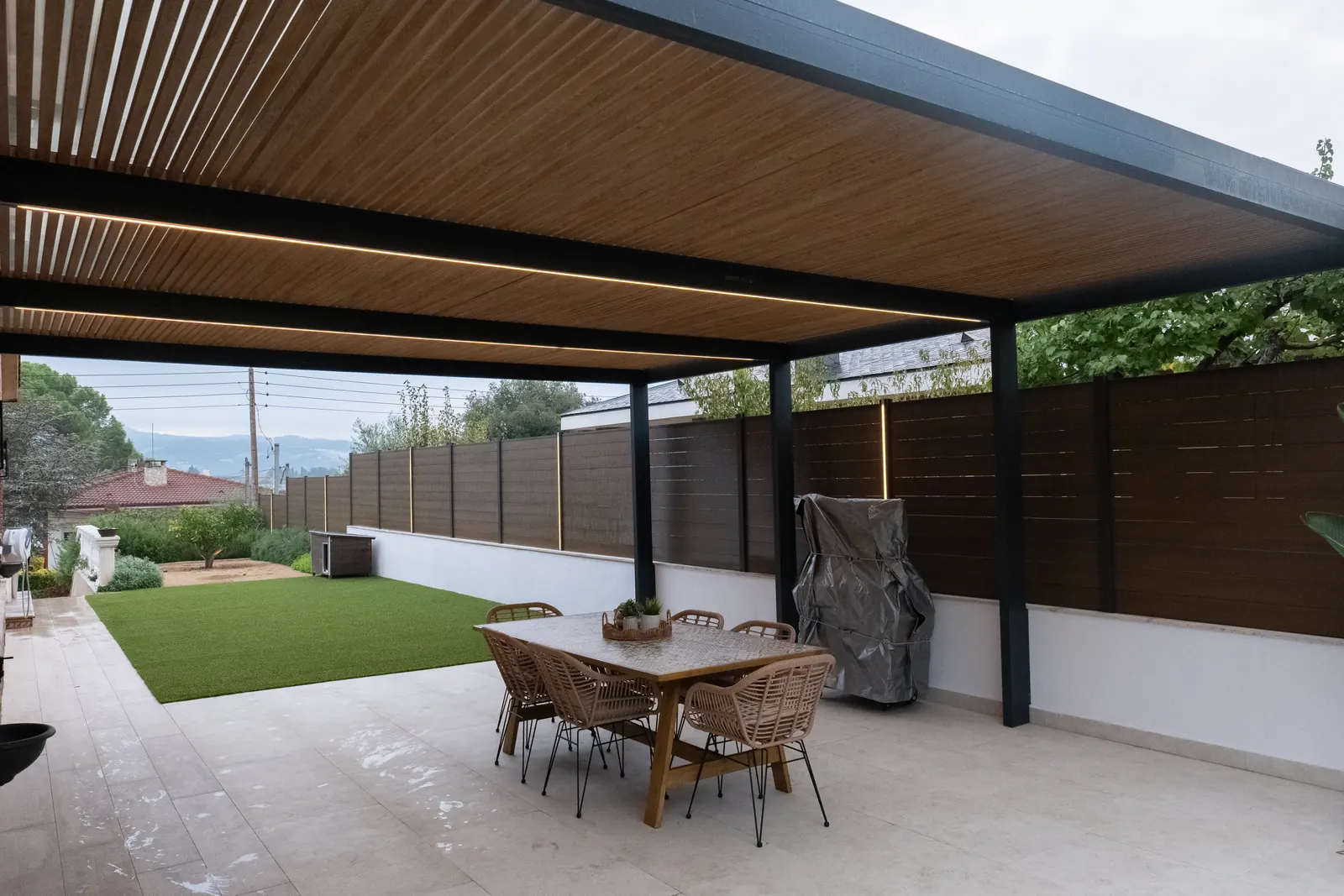 Comedor exterior cubierto por pérgola de lamas