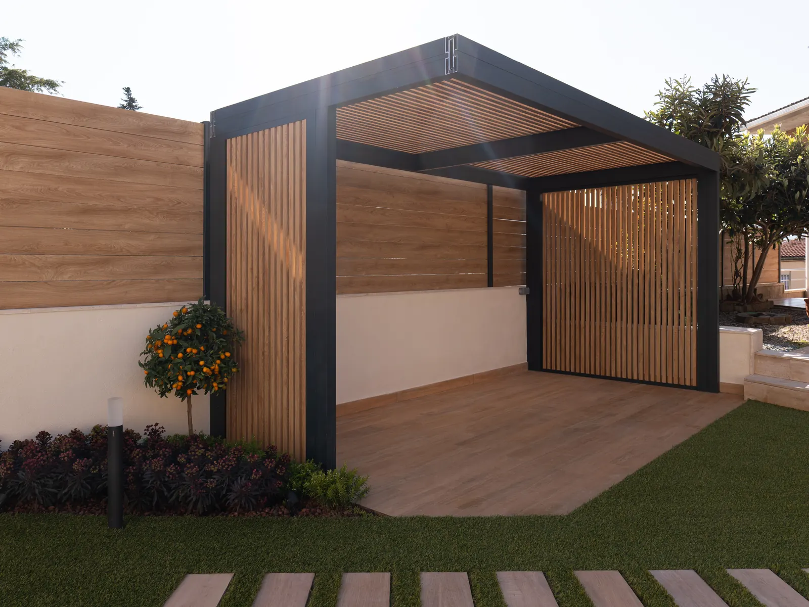 Pérgola de estructura oscura con panel lateral de privacidad