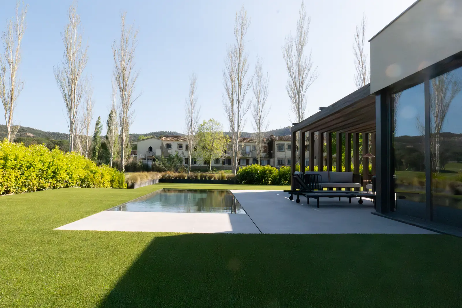 Zona de sombra con pérgola negra junto a piscina