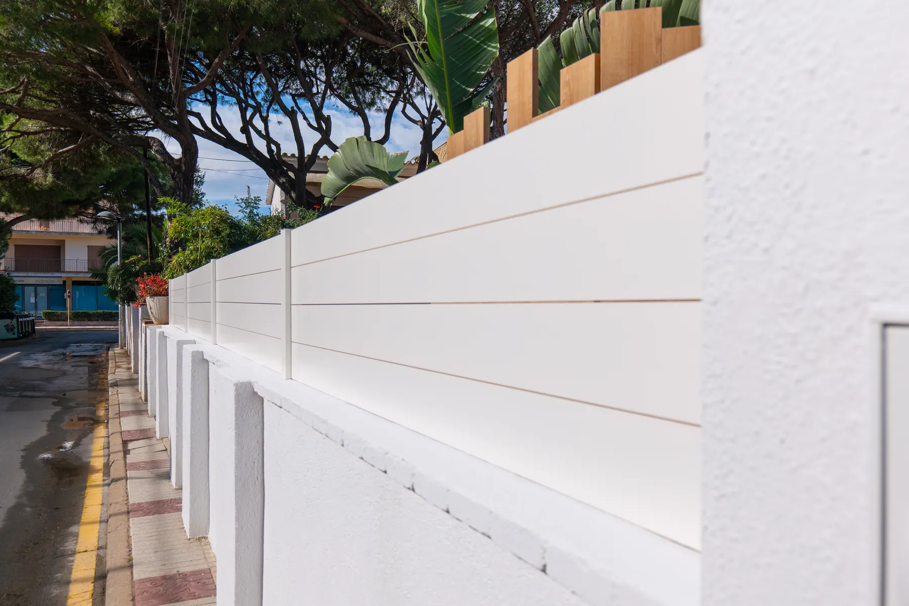 Valla de aluminio lacado blanco instalada sobre muro exterior