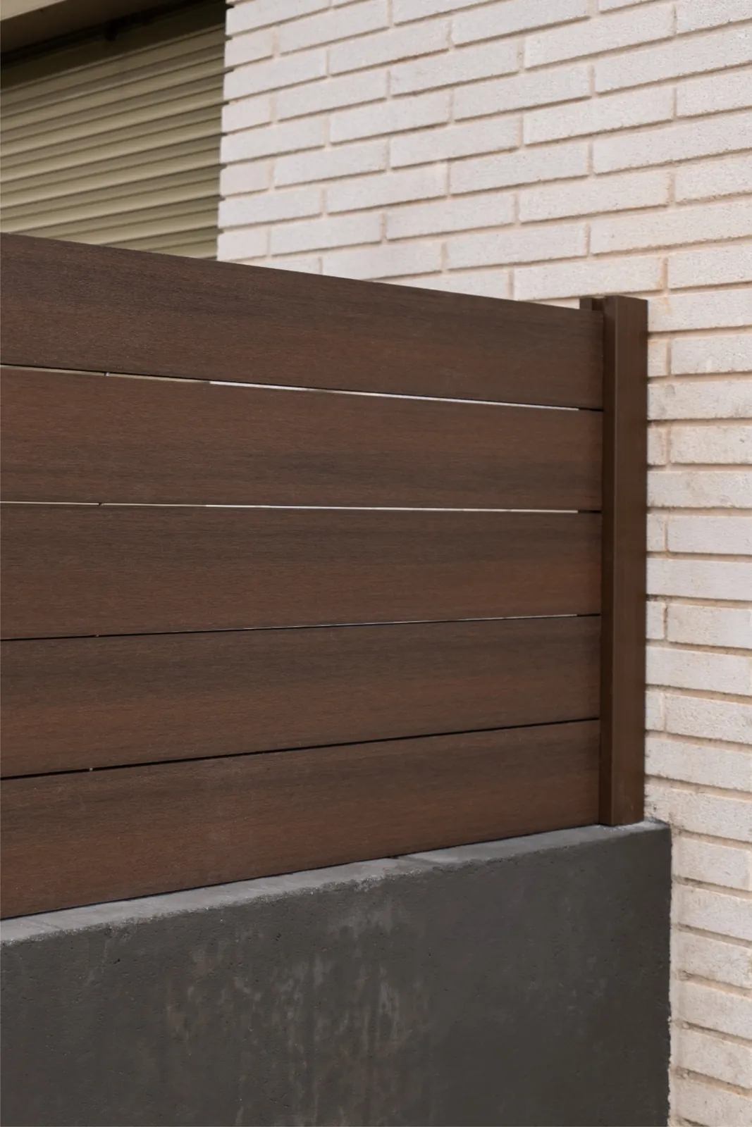 Valla Light Walnut instalada sobre un murete exterior en Terrassa