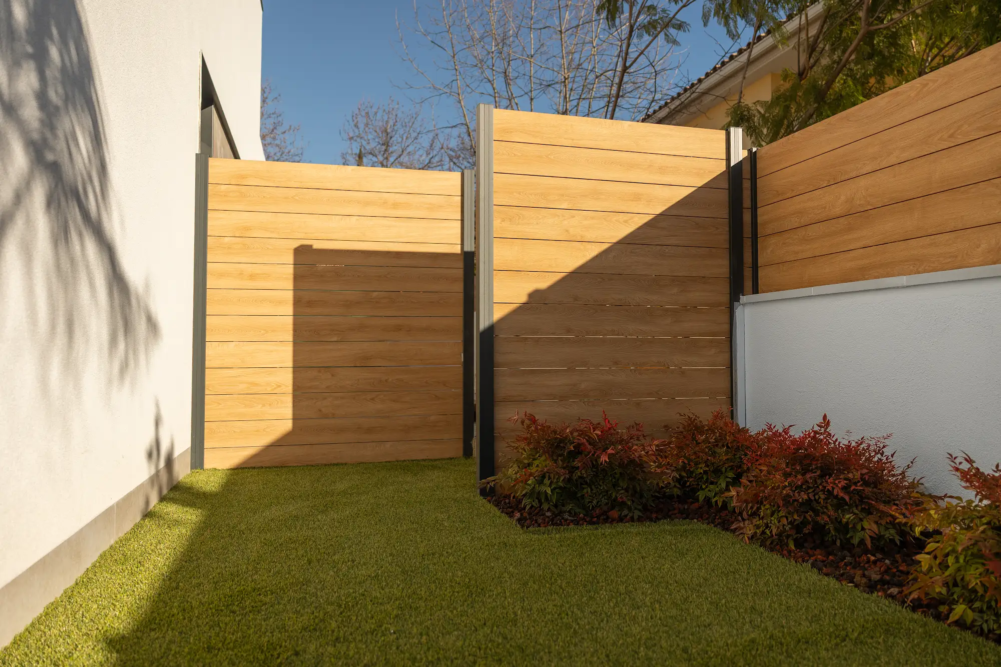 Valla efecto madera con postes antracita instalada en un jardín