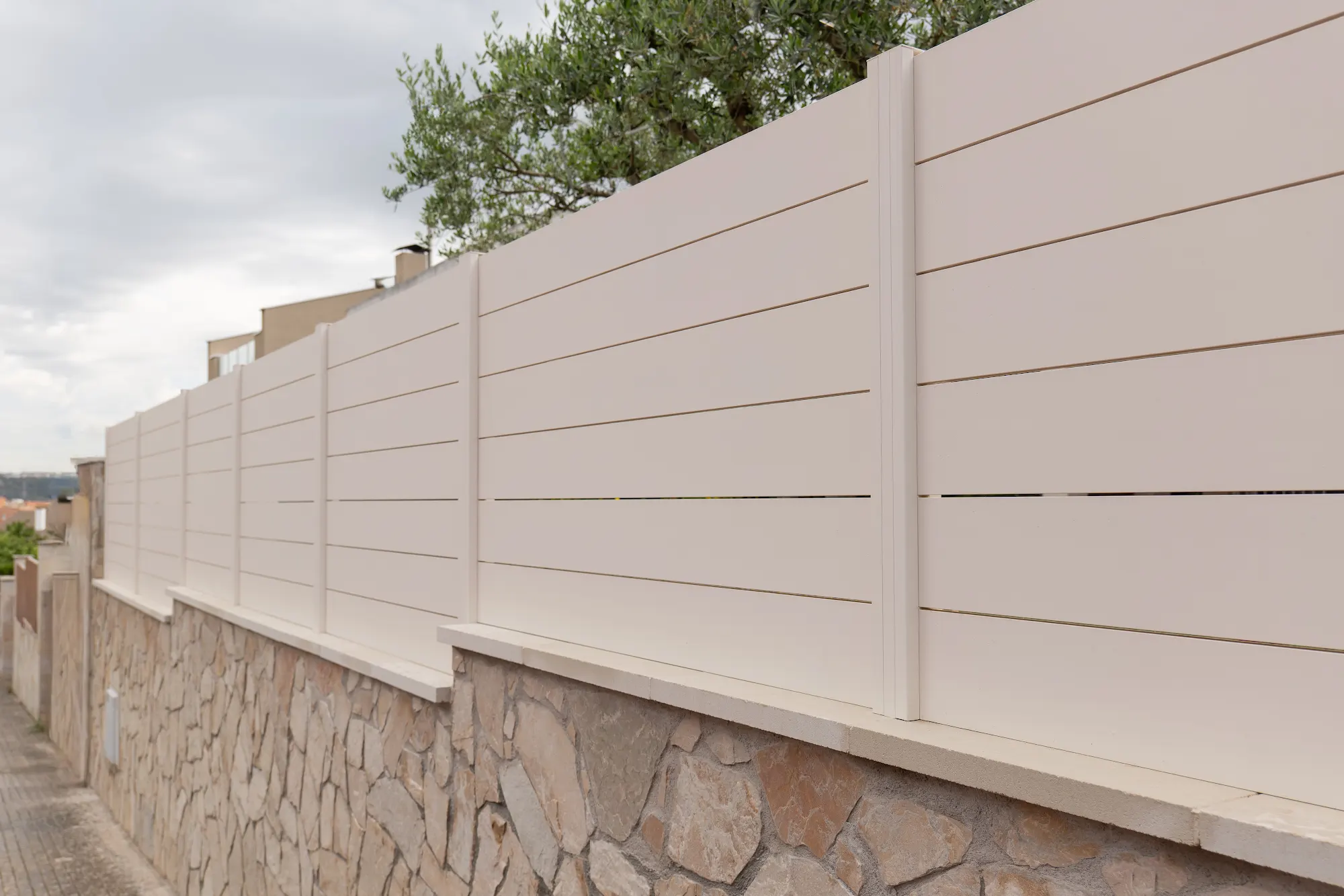 Valla blanca instalada sobre un muro de piedra