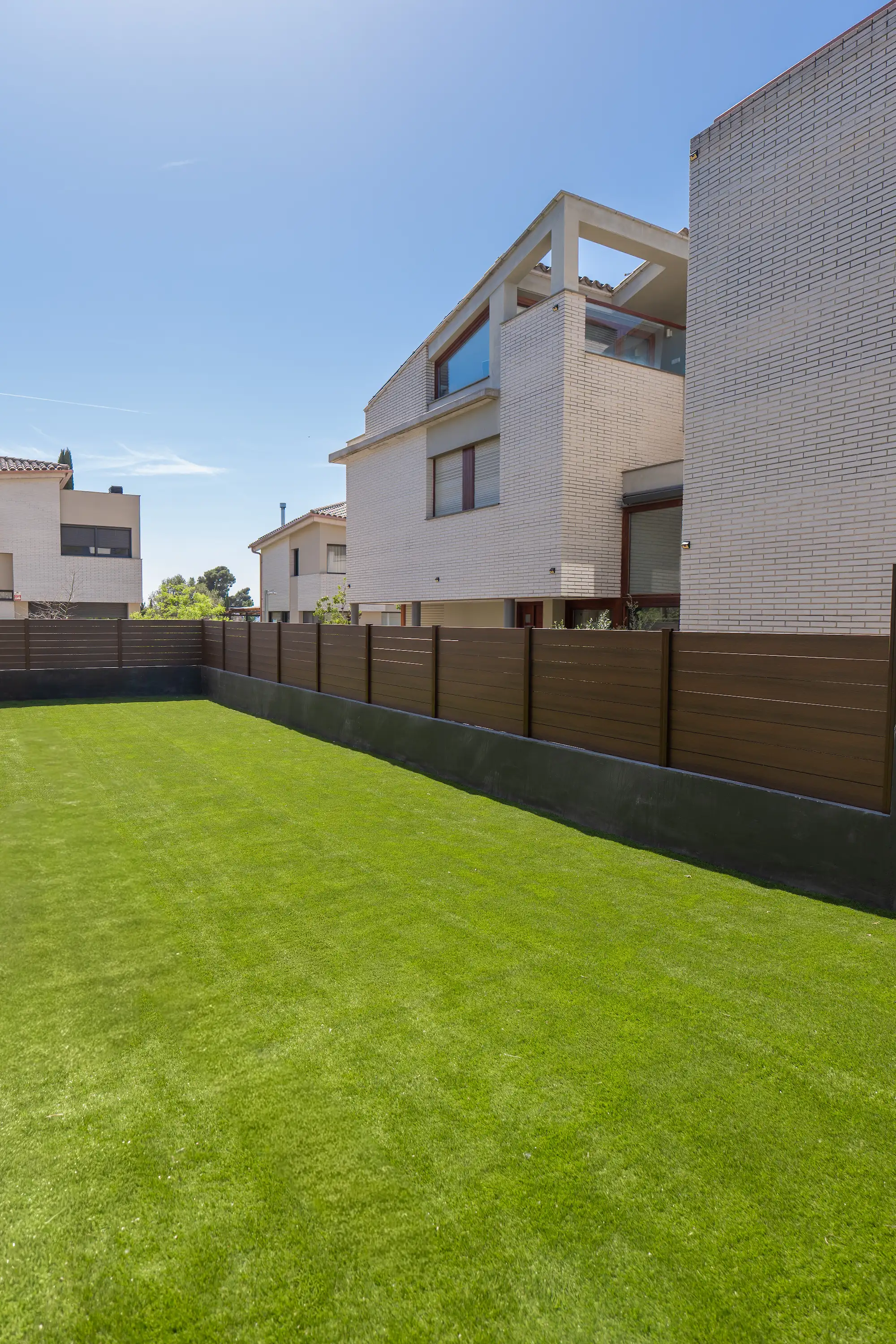 Valla marrón integrada con césped en un jardín residencial