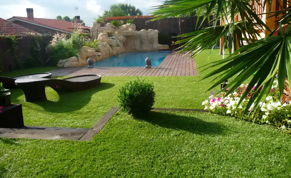 Jardín residencial con césped, piscina y vegetación ornamental en Manresa