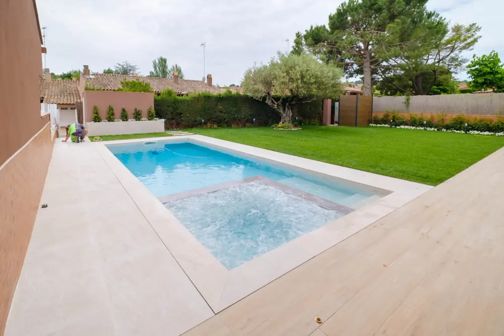 Piscina de obra con jacuzzi integrado, cesped y zona perimetral