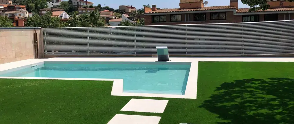 Jardín con piscina y césped ejecutado en entorno residencial