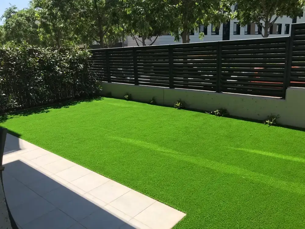 Jardín residencial con césped artificial y cerramiento contemporáneo