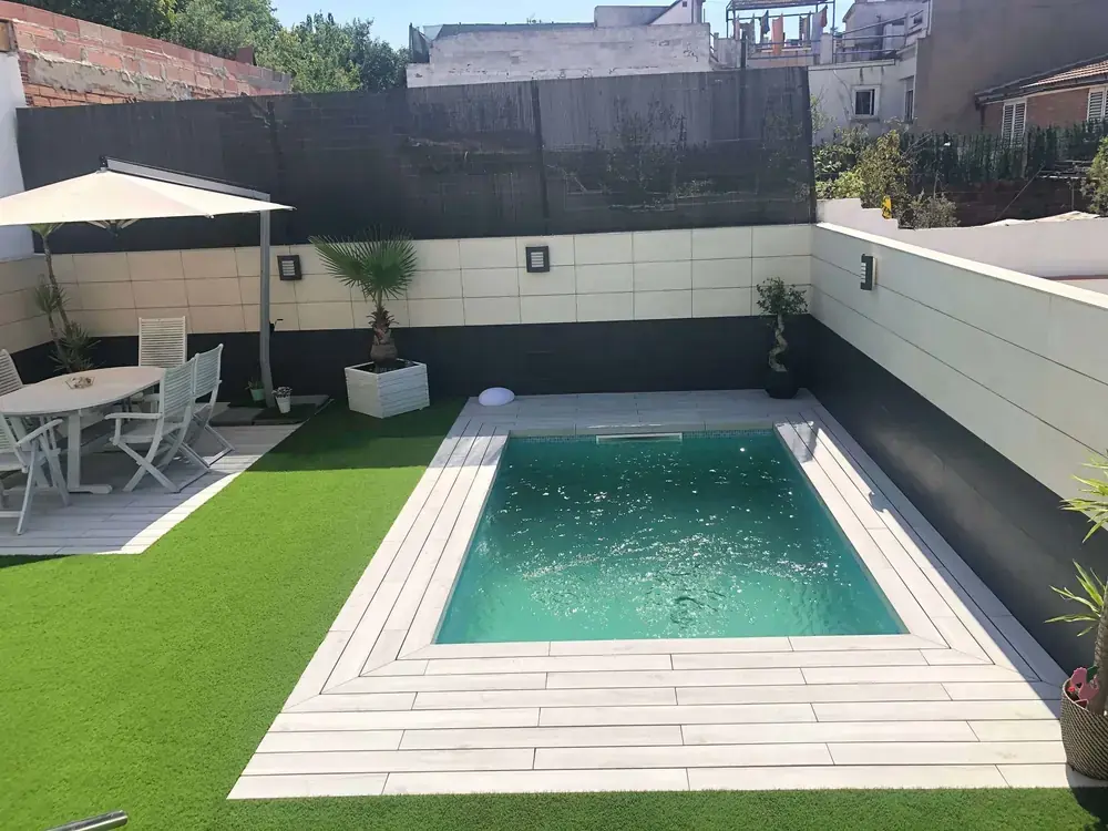 Piscina residencial con pavimento efecto madera y césped artificial