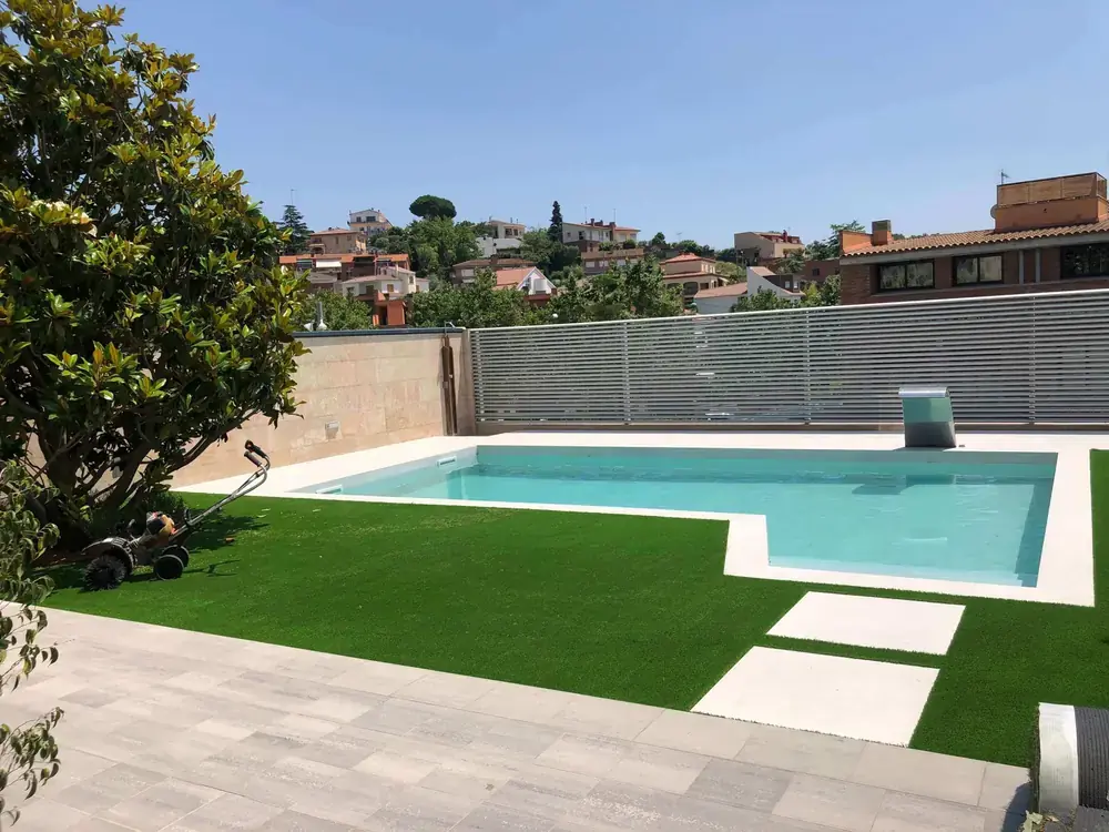 Zona de piscina integrada con jardín y pavimento exterior