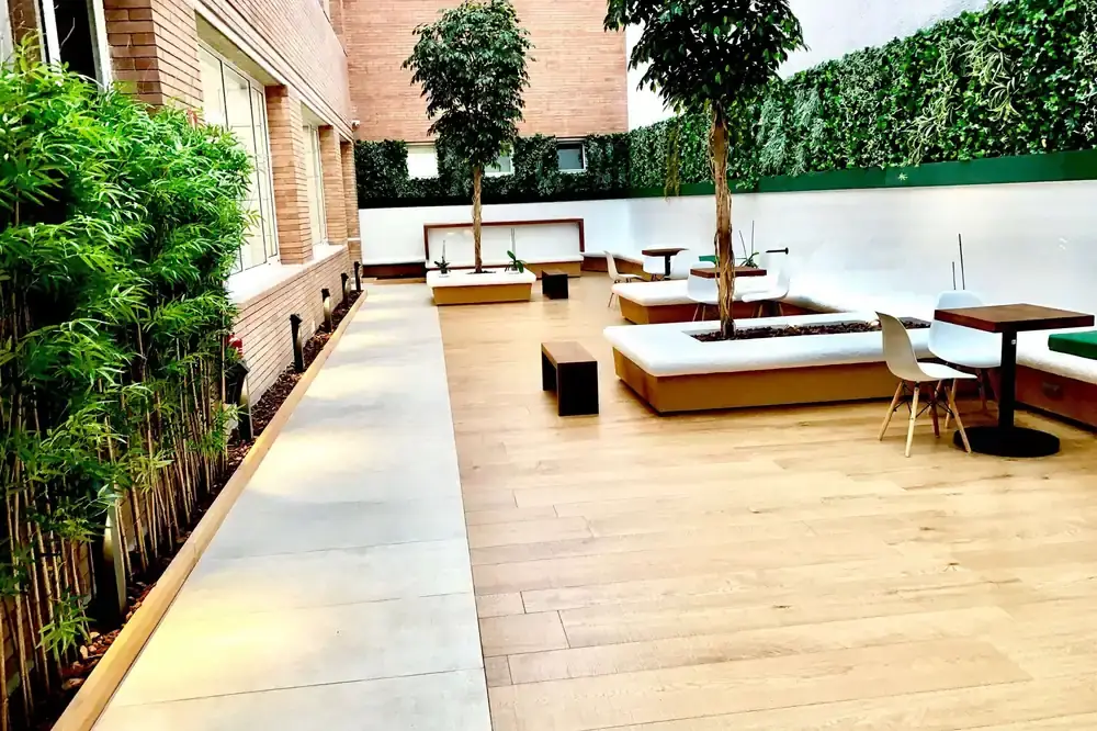 Tarima exterior porcelánica en patio urbano con jardineras