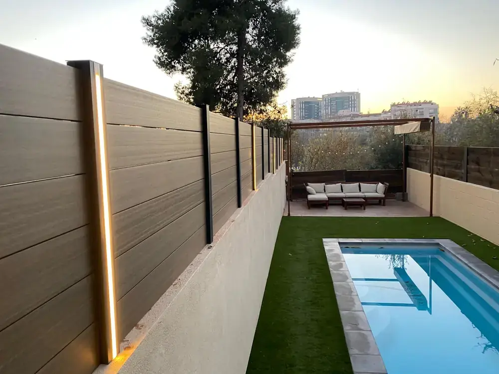 Cerramiento exterior WPC con postes iluminados junto a piscina
