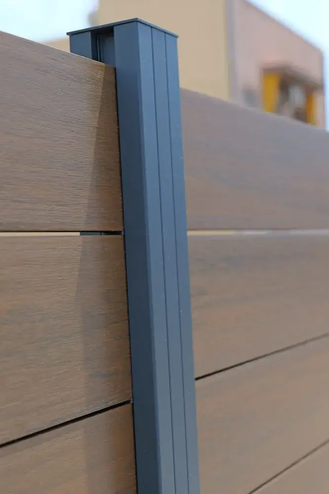 Detalle de perfil de aluminio y lamas efecto madera en valla composite