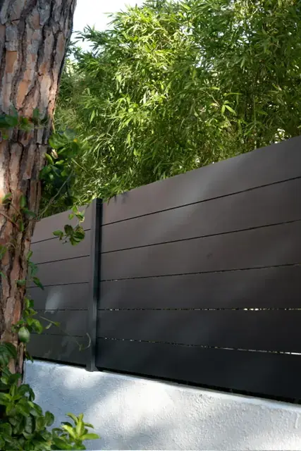 Valla de composite efecto madera instalada sobre murete blanco